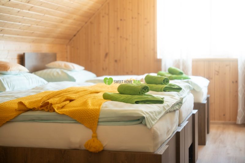 Penzión pri Bešeňovej – podnikateľská príležitosť v srdci Liptova - Izba s dvoma posteľami, žltou dekou a dreveným obložením v Hotely a penzióny.