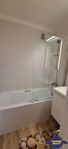 REZERVOVANÉ: 3 izbový byt + 2x balkón, komplet.rekonštr. - KOMÁRNO - Kúpeľňa v 3-izbovom byte s vaňou, bielymi obkladmi a podlahou s dreveným dekorom.