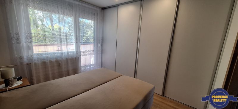 REZERVOVANÉ: 3 izbový byt + 2x balkón, komplet.rekonštr. - KOMÁRNO - Spálňa v 3-izbovom byte s veľkou šatníkovou skriňou a oknom so záclonami.
