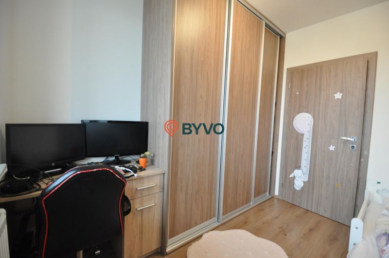 3-IZBOVÝ TEHLOVÝ BYT V DUBNICI NAD VÁHOM | 68 m² | BALKÓN | VLASTNÉ KÚ - Pracovný kút so stolom, dvoma monitormi, šatníkovou skriňou a podlahou s dreveným dekorom.
