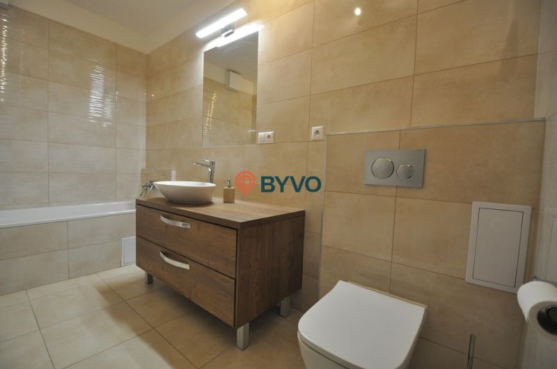 3-IZBOVÝ TEHLOVÝ BYT V DUBNICI NAD VÁHOM | 68 m² | BALKÓN | VLASTNÉ KÚ - Kúpeľňa s vaňou, umývadlom na drevenom dekore a béžovými obkladmi v 3-izbovom byte.