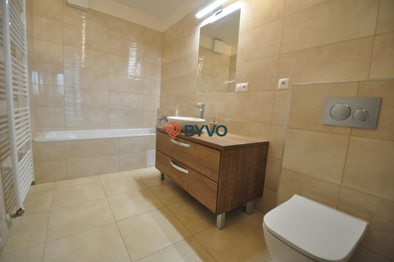 3-IZBOVÝ TEHLOVÝ BYT V DUBNICI NAD VÁHOM | 68 m² | BALKÓN | VLASTNÉ KÚ - Kúpeľňa v 3-izbovom byte s vaňou, umývadlom a skrinkou s dreveným dekorom.