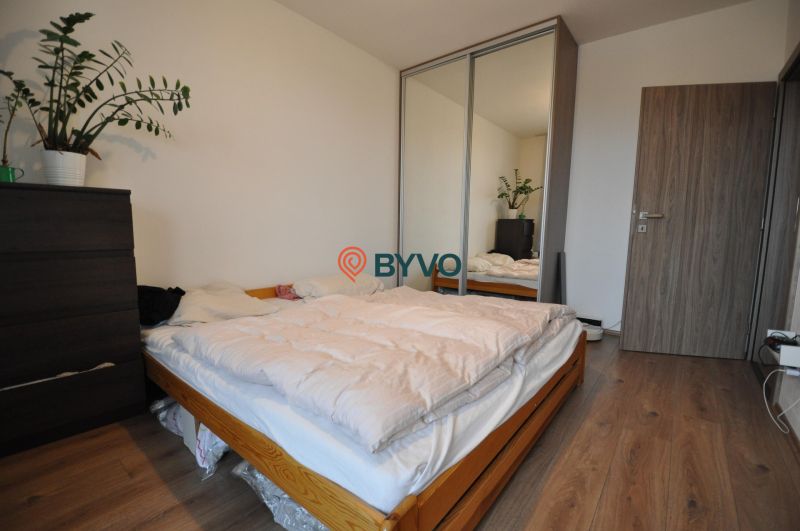 3-IZBOVÝ TEHLOVÝ BYT V DUBNICI NAD VÁHOM | 68 m² | BALKÓN | VLASTNÉ KÚ - Spálňa s posteľou, skriňou so zrkadlom a podlahou s dreveným dekorom v 3-izbovom byte.
