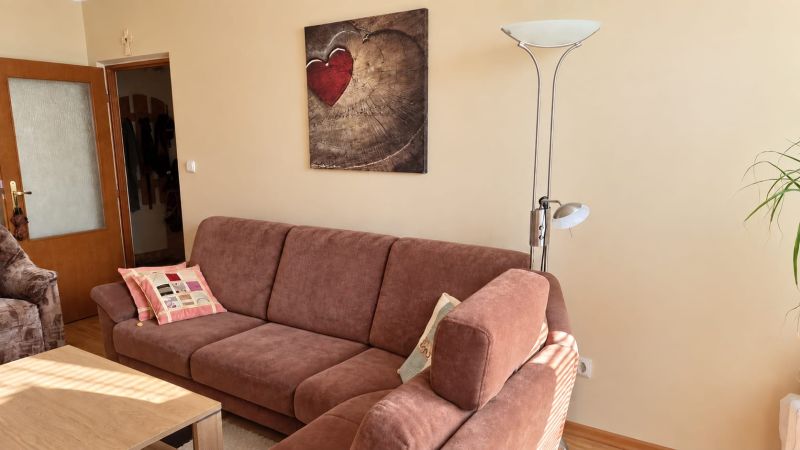 PRENÁJOM | 3-IZBOVÝ BYT | 80 m² | 2 BALKÓNY | ZARIADENÝ | CENTRUM I  - Pohodlná obývačka s pohovkou, lampou a umeleckým obrazom v 3-izbovom byte.