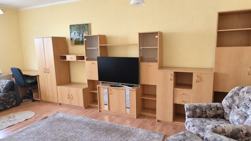 PRENÁJOM | 3-IZBOVÝ BYT | 80 m² | 2 BALKÓNY | ZARIADENÝ | CENTRUM I  - Obývačka v 3-izbovom byte s podlahou s dreveným dekorom, svetlý nábytok, televízor.