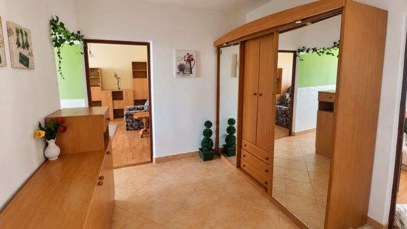 PRENÁJOM | 3-IZBOVÝ BYT | 80 m² | 2 BALKÓNY | ZARIADENÝ | CENTRUM I  - Chodba v 3-izbovom byte s drevenými skriňami a dekoráciami na beige dlažbe.
