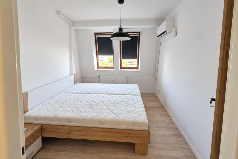 Na prenájom 2-izbový byt s balkónom v Bratislave– Rača - Spálňa s posteľou, klimatizáciou a podlahou s dreveným dekorom v 2-izbovom byte.