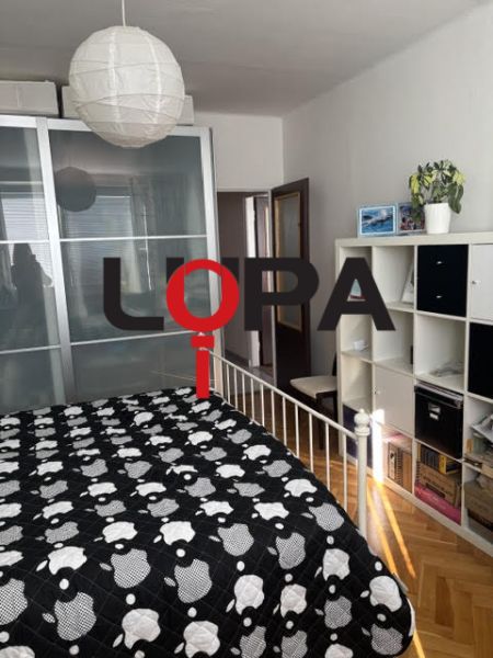 PREDAJ  2 izb. bytu s balkónom v Komárne - Spálňa v 2-izbovom byte s úložným priestorom, posteľou a podlahou s dreveným dekorom.
