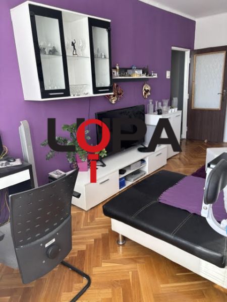 PREDAJ  2 izb. bytu s balkónom v Komárne - Obývacia izba v 2-izbovom byte so sedačkou a nábytkom, podlaha s dreveným dekorom.