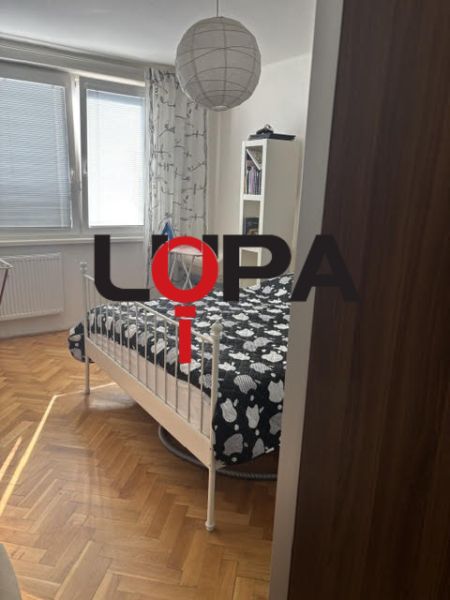 PREDAJ  2 izb. bytu s balkónom v Komárne - Spálňa v 2-izbovom byte s posteľou a podlahou s dreveným dekorom.