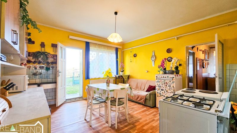 PREDAJ - 4 izbový rodinný dom, Kráľov Brod - Kuchyňa v rodinnom dome so žltými stenami, jedálenským stolom a kvetinovou dekoráciou.
