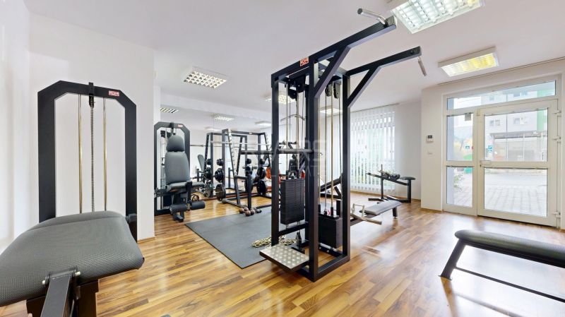 RIVERS | Nebytový priestor v Dúbravke na predaj - Posilňovňa s rôznym fitness vybavením a podlahou s dreveným dekorom v obchodných priestoroch.