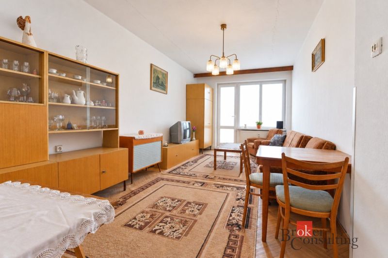 Svetlý a teplý 2-izbový byt s balkónom v centre Spišskej Novej Vsi (52 - Obývacia izba 2-izbového bytu s retro nábytkom, kobercom a sklom vitríny.