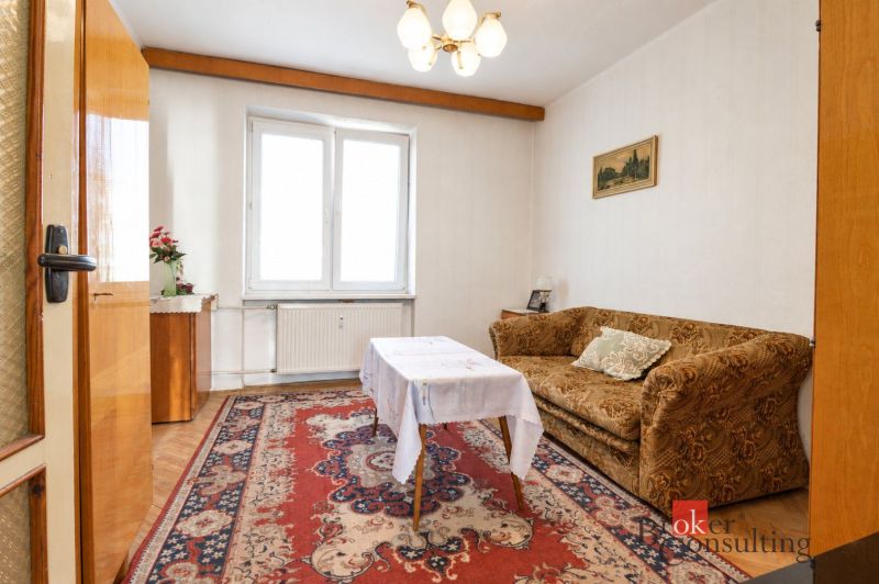 Svetlý a teplý 2-izbový byt s balkónom v centre Spišskej Novej Vsi (52 - Obývacia izba v 2-izbovom byte s kobercom a pohovkou, podlaha s dreveným dekorom.