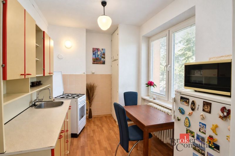 Svetlý a teplý 2-izbový byt s balkónom v centre Spišskej Novej Vsi (52 - Kuchyňa v 2-izbovom byte s podlahou s dreveným dekorom, jedálenským stolom a modernou výbavou.