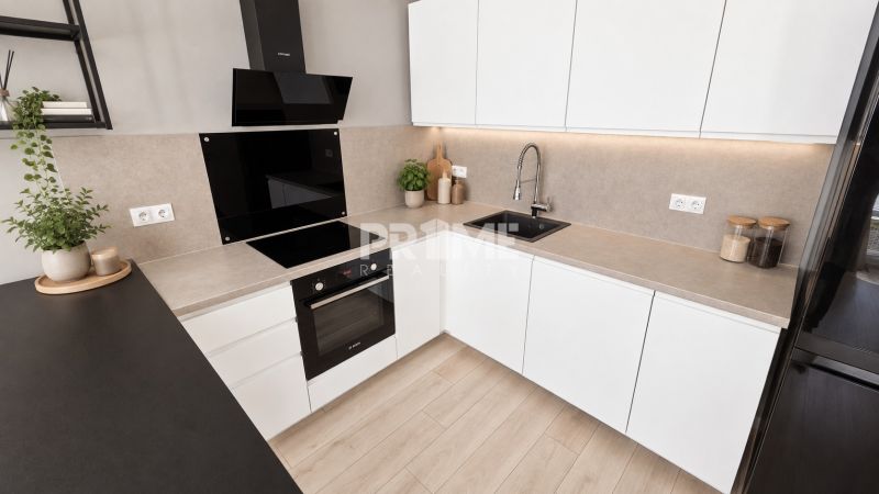 Moderný 2-izbový apartmán, balkón, sklad, Šancová-novostavba PREMIÈRE - Kuchyňa v 2-izbovom byte s bielymi skrinkami, varnou doskou a podlahou s dreveným dekorom.