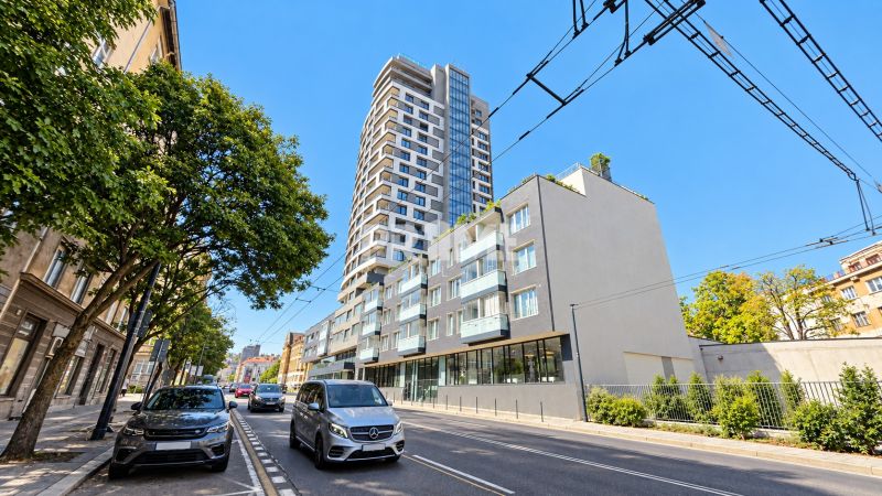 Moderný 2-izbový apartmán, balkón, sklad, Šancová-novostavba PREMIÈRE - Šancová ulica v Bratislave - Staré Mesto s modernou výškovou budovou a zeleňou.