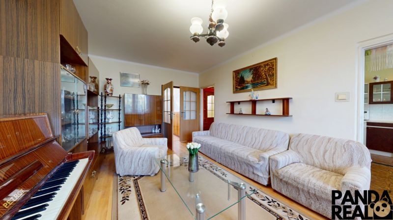 3.izbový byt so záhradou /420 m²/ a chatkou BOŠANY - Obývacia izba so svetlým nábytkom, klavírom a skleneným stolíkom v 3-izbovom byte.