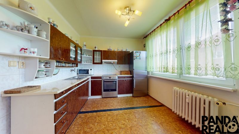 3.izbový byt so záhradou /420 m²/ a chatkou BOŠANY - Kuchyňa v 3-izbovom byte s linkou, záclonami a podlahou s dreveným dekorom.