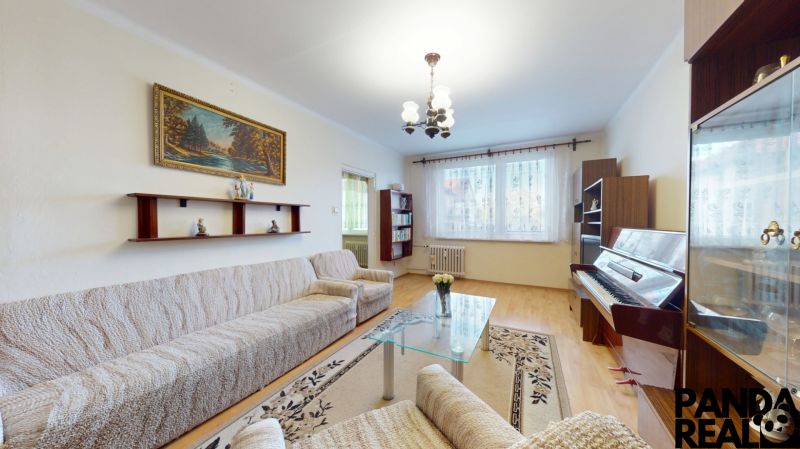 3.izbový byt so záhradou /420 m²/ a chatkou BOŠANY - Obývacia izba v 3-izbovom byte, pohovka, klavír, koberec, podlaha s dreveným dekorom.