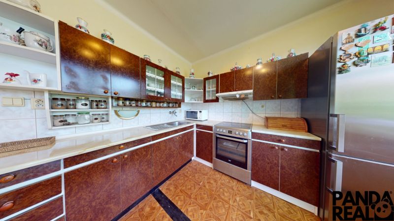 3.izbový byt so záhradou /420 m²/ a chatkou BOŠANY - Kuchyňa v 3-izbovom byte s tmavými skriňami a podlahou s dreveným dekorom.