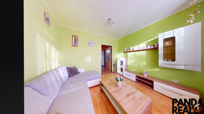 3.izbový byt so záhradou /420 m²/ a chatkou BOŠANY - Obývačka v 3-izbovom byte s podlahou s dreveným dekorom a svetlozelenými stenami.