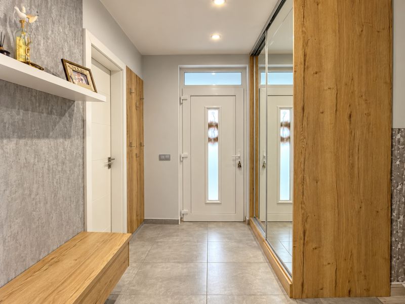 Predaj 4i samostatný rodinný dom, 400 m2 pozemok, Mosonmagyaróvár - Interiér rodinného domu s dreveným dekorom a veľkým zrkadlom v predsieni.