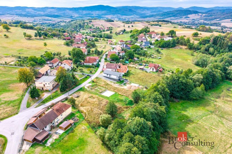 Pozemok na predaj v Detve, Skliarovo, aj so základovou platňou - Letecký pohľad na obytné pozemky v meste Detva s okolitou prírodou a budovami.