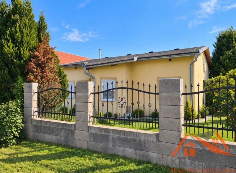 Na predaj rodinný dom s krásnym rozsiahlym pozemkom Martovce! - Rodinný dom v Martovciach so záhradou obklopený zelenými stromami a plotom.