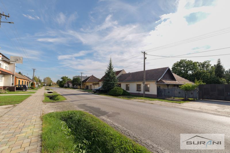 Starší rodinný dom s veľkou záhradou v obci Štefanová | okres Pezinok - Rodinné domy na Hlavnej ulici v Štefanovej s upravenou záhradou a jasnou oblohou.