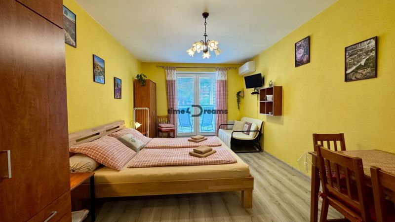 NA PREDAJ apartmán v Podhájskej  - Interiér s posteľou, stoličkami a podlahou s dreveným dekorom v Rekreačnom apartmáne.