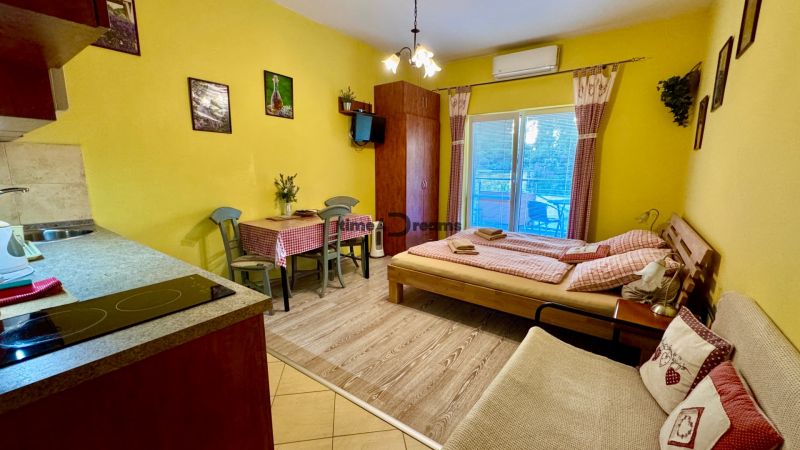 NA PREDAJ investičný apartmán v Podhájskej - Interiér rekreačného apartmánu s podlahou s dreveným dekorom, jedálenským stolom a posteľou.