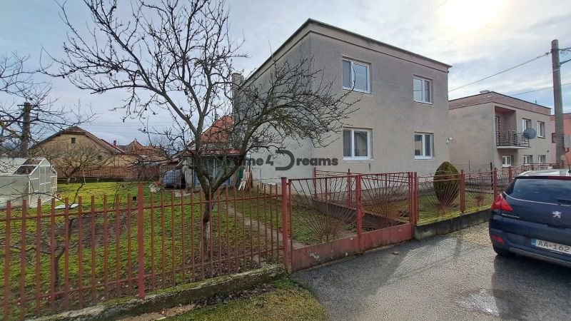 NA PREDAJ 6 izbový rodinný dom v obci Hrušovany  - Rodinný dom v Hrušovanoch s upravenou záhradou, skleníkom a kovovým plotom.