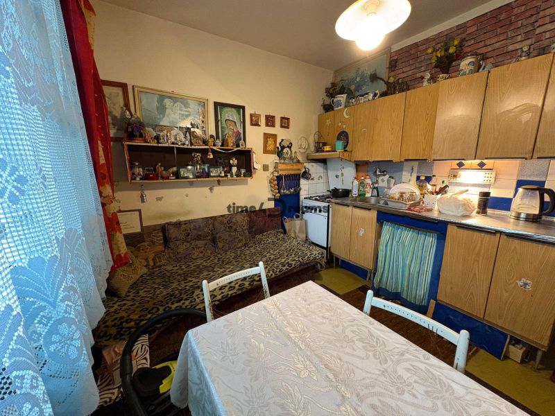 NA PREDAJ 2 izbový byt Nitra - Chrenová - Kuchyňa v 2-izbovom byte so staršími skrinkami a dekoráciami na policiach.