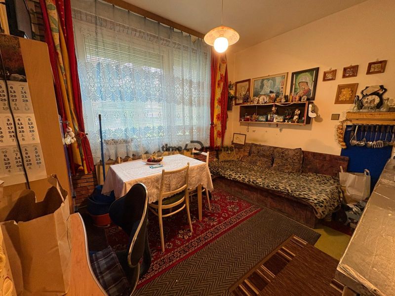 NA PREDAJ 2 izbový byt Nitra - Chrenová - Izba v 2-izbovom byte s gaučom, stolom a dekoráciami na stenách.