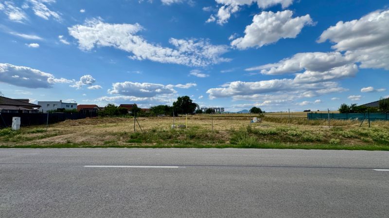NA PREDAJ Stavebný pozemok v obci Golianovo - Stavebný pozemok na bývanie v Golianove, plný zelene a modrej oblohy.