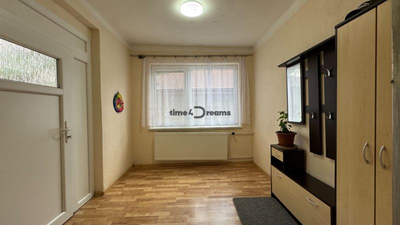 NA PREDAJ Rodinný dom - Šurany - Nitriansky Hrádok, EXKLUZÍVNE - Vstupná chodba s drevenou podlahou, bielou stenou a nábytkom v rodinnom dome.