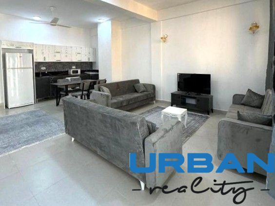 2-IZBOVÝ CONDO APARTMÁN PRI PLÁŽI, MBWENI, ZANZIBAR - Moderná obývačka v 2-izbovom byte s veľkou sedacou súpravou a kuchynským kútom.
