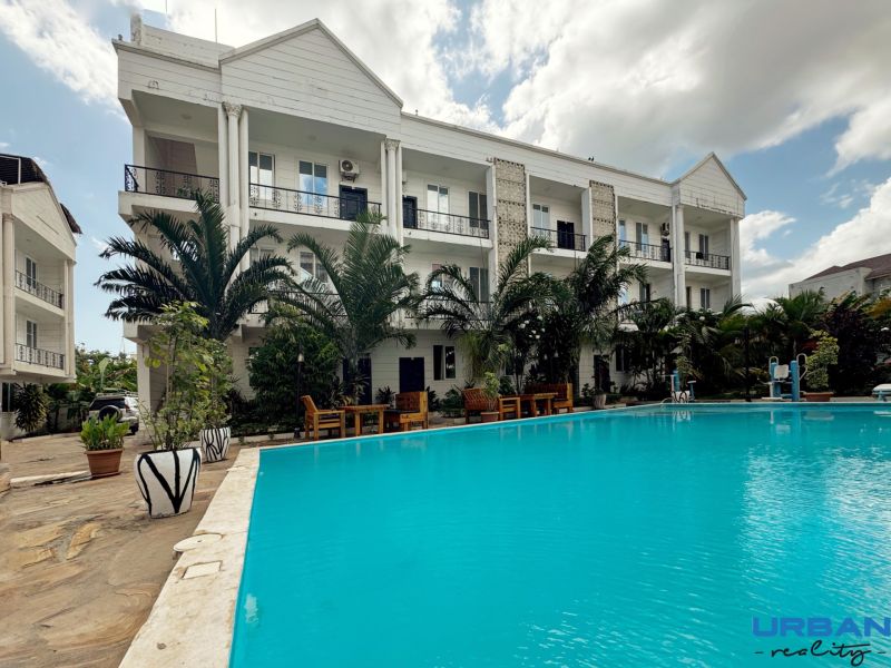 2-IZBOVÝ CONDO APARTMÁN PRI PLÁŽI, MBWENI, ZANZIBAR - Budova pri bazéne a palmách v časti Mbweni v Zanzibare.