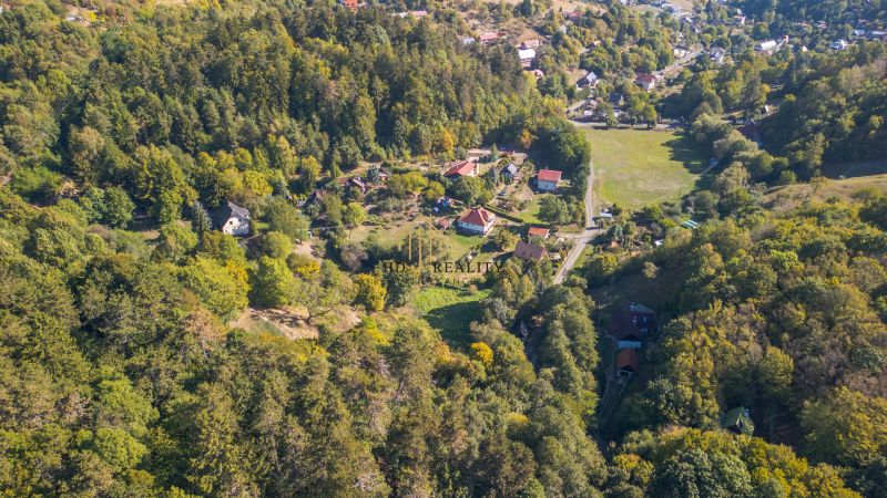 Predaj, rekreačné pozemky Štiavnické Bane - Letecký pohľad na zelené Rekreačné pozemky v Štiavnických Baních so strechami domov.