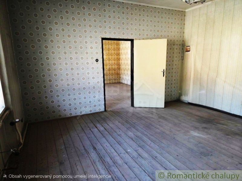 Multifunkčná budova v srdci Modrého Kameňa v okrese Veľký Krtíš - Miestnosť s tapetami a podlahou s dreveným dekorom, v pozadí ďalšia izba.