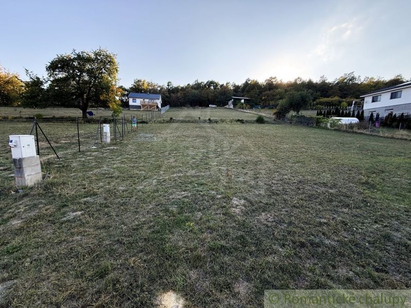 3106m2 stavebný pozemok nad priehradou v Krupine - Záhrady v Krupine, domy na svahu, tráva a stromy, vidno rozvodnú skriňu.