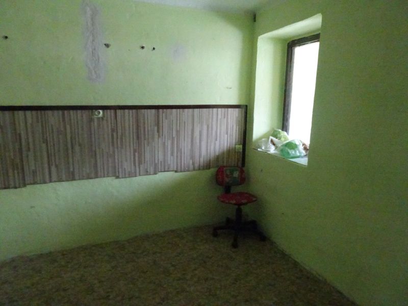 Na predaj rodinný dom Diviaky nad Nitricou - Izba s kreslom, zelenými stenami a zaplneným parapetom v rodinnom dome.