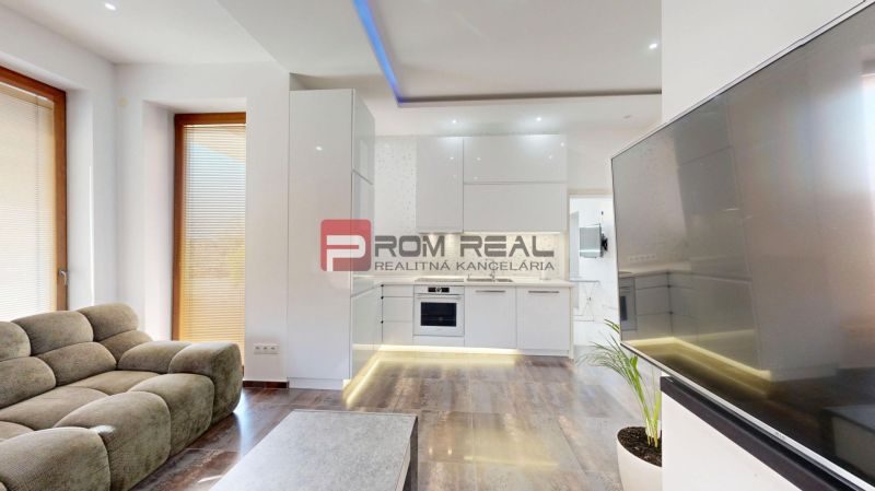 6i DVOJGENERAČNÝ DOM PO REKONŠTRUKCII S VEĽKÝM POZEMKOM A SMARTHOME –  - Obývačka v rodinnom dome s podlahou s dreveným dekorom, kuchyňou a pohodlnou sedačkou.