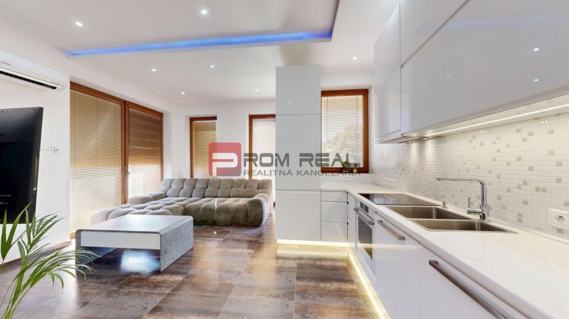 6i DVOJGENERAČNÝ DOM PO REKONŠTRUKCII S VEĽKÝM POZEMKOM A SMARTHOME –  - Obývací priestor s rohovou sedačkou a kuchyňou v rodinnom dome.