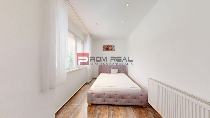 6i DVOJGENERAČNÝ DOM PO REKONŠTRUKCII S VEĽKÝM POZEMKOM A SMARTHOME –  - Spálňa v Rodinnom dome s posteľou, oknom a podlahou s dreveným dekorom.