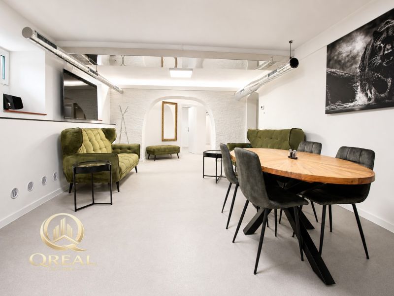 **Hotový priestor. Povolené ubytovanie. Pripravené zarábať**Airbnb** - Priestranná obývacia izba s dreveným jedálenským stolom a zelenými sedačkami.