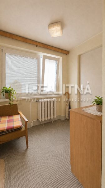 RODINNÝ DOM S VÝNIMOČNOU ZÁHRADOU, 1 141 M², BANSKÁ BYSTRICA  - Izba v rodinnom dome s kreslom, skrinkou, rastlinami a radiátorom pod oknom.