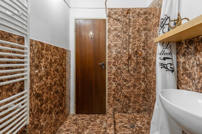 I VILA REIM – Exkluzívna investičná príležitosť  - Kúpeľňa na Chate s mramorovým obkladom a bielym radiátorom.