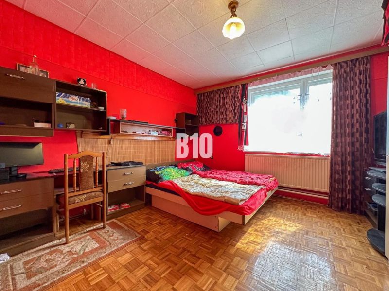 Priestranný 5-izbový rodinný dom na veľkom pozemku pri lese - Interiér rodinného domu s červenými stenami, stolom, posteľou a podlahou s dreveným dekorom.